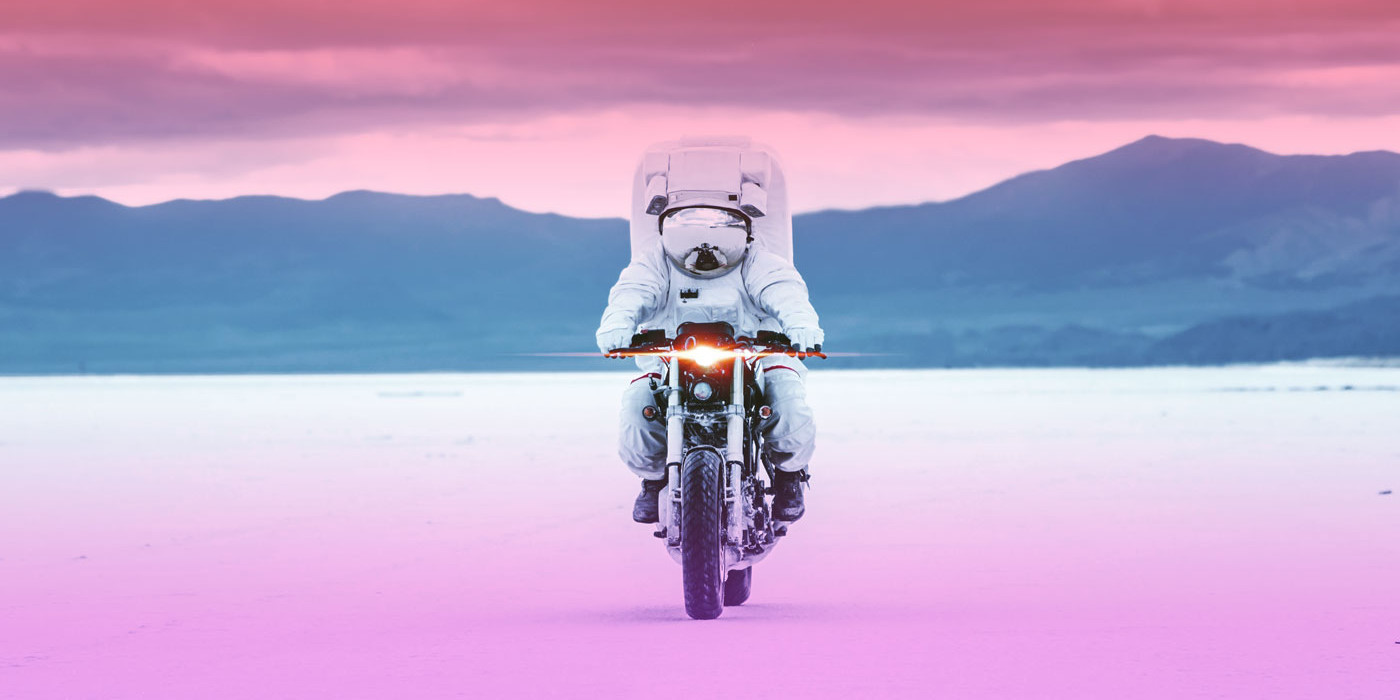 an astronaut on a motorcycle with mountains in the background